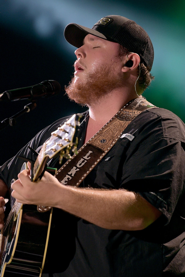 Кантри исполнитель Люк Комбс с гитарой поет на сцене