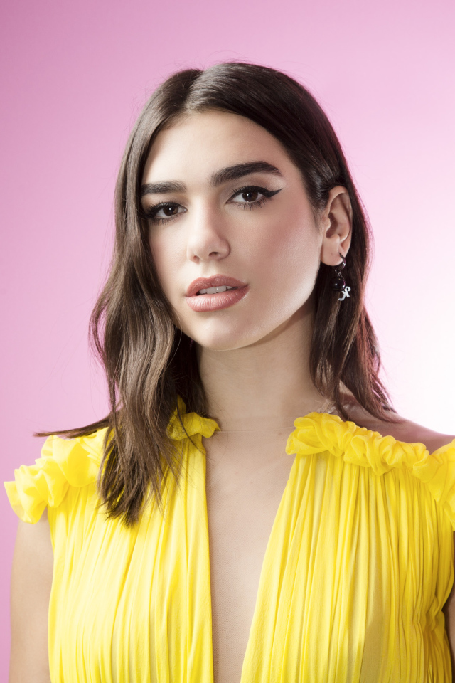 Милая девушка, певица Дуа Липа в желтом платье на розовом фоне