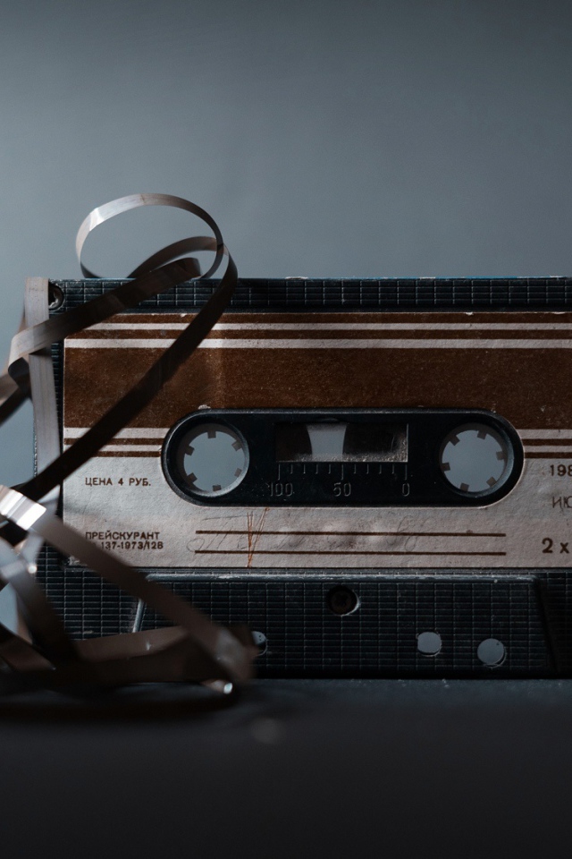 Старая кассета с вытянутой пленкой на сером фоне 