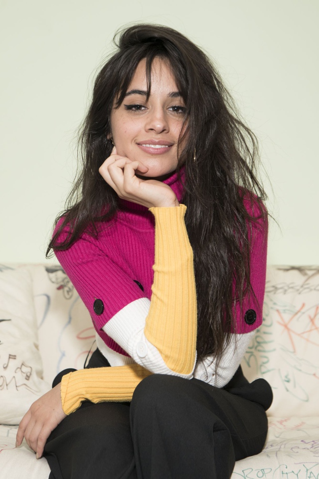 Улыбающаяся Камила Кабельо сидит на диване