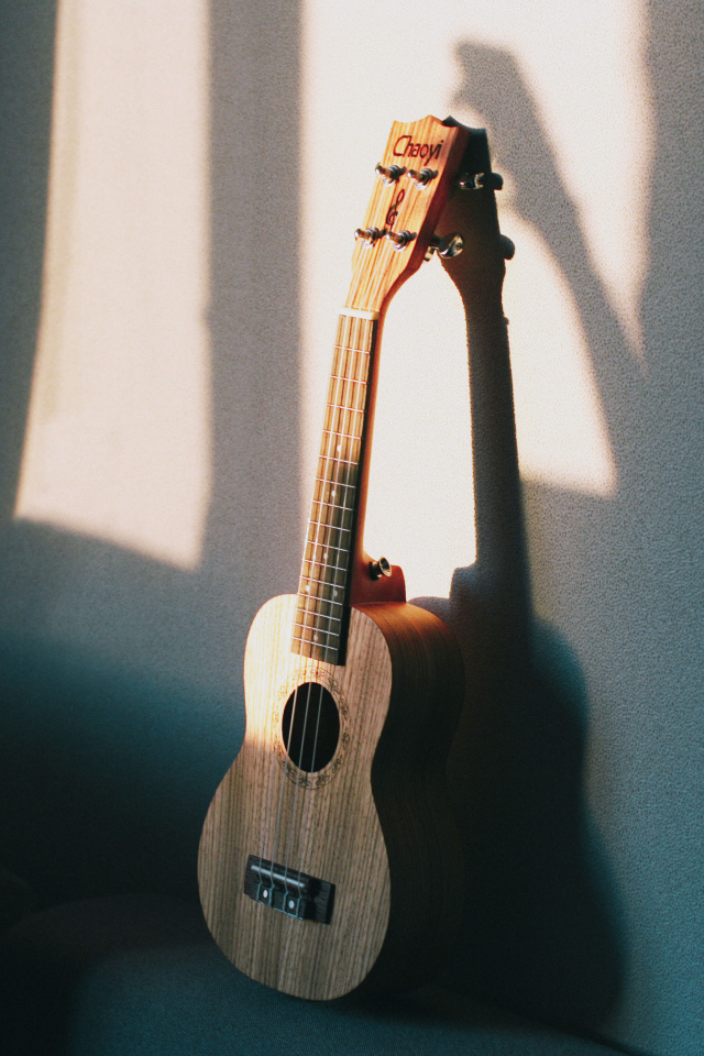 Желтая гитара стоит у серой стены