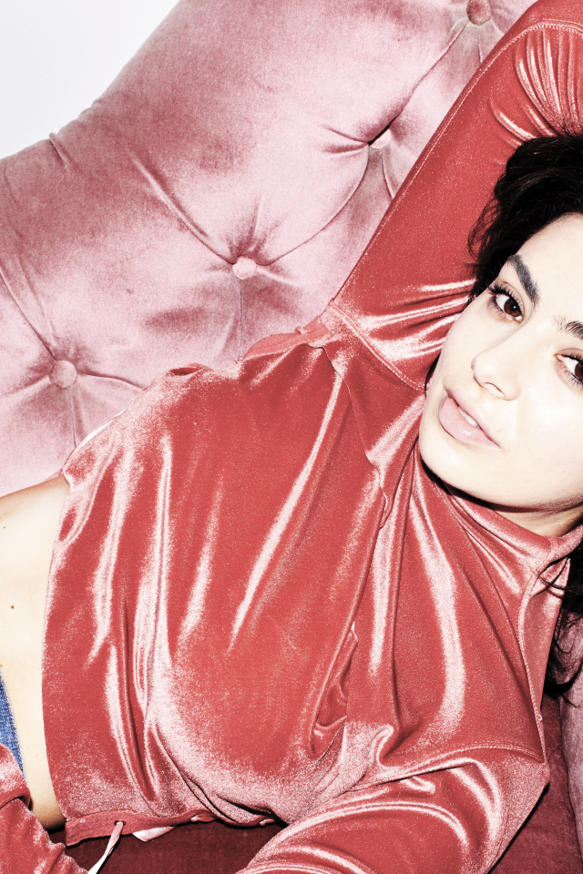 Молодая девушка Charli XCX лежит на диване