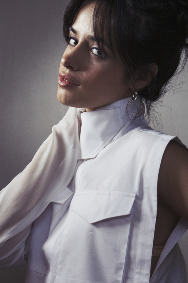 Молодая певица Камила Кабельо в белом костюме у стены