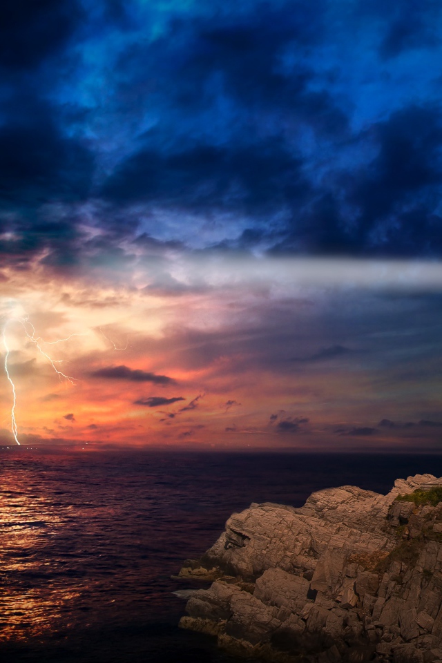 Маяк на берегу моря освещает грозовое небо 