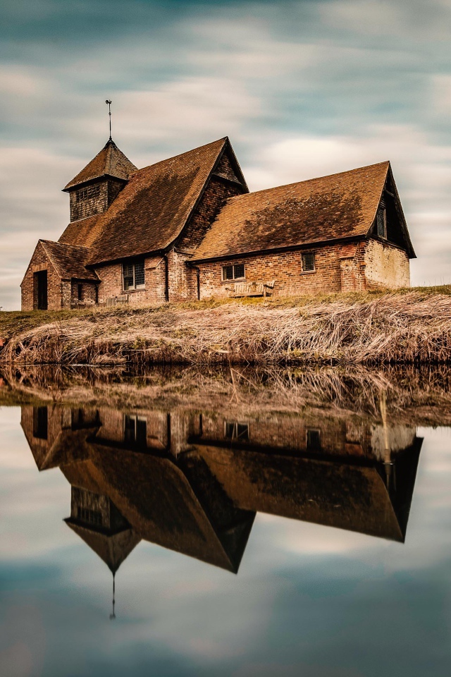Старый дом на берегу реки отражается в воде