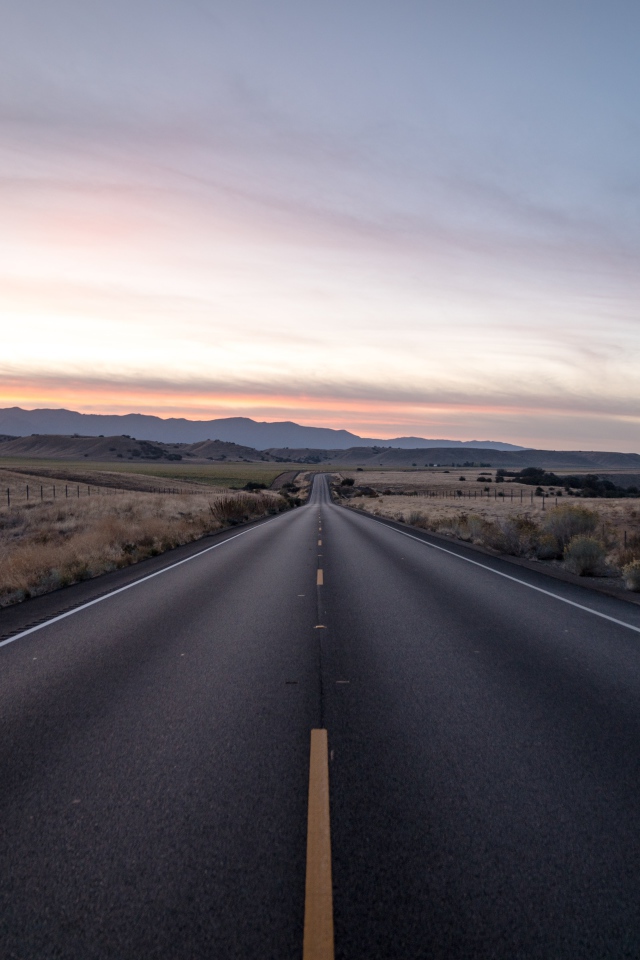 Асфальтная дорога уходит вдаль на фоне неба