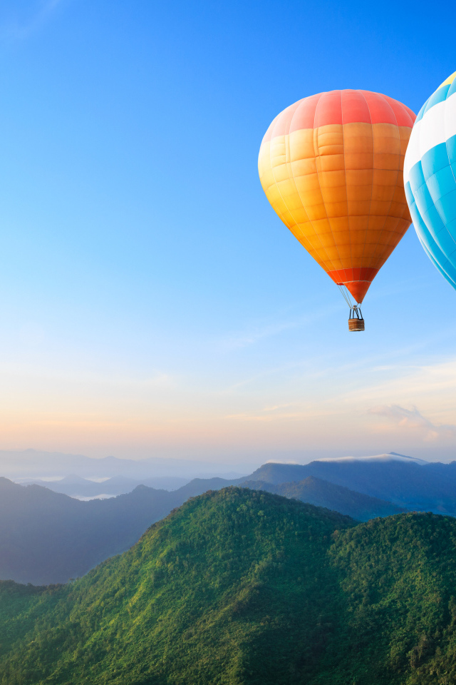 Большие воздушные шары в голубом небе над зелеными холмами