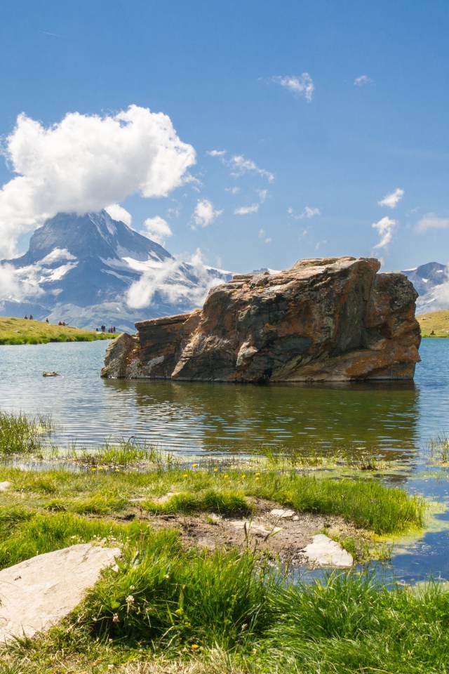 Большой камень в воде на фоне голубого неба