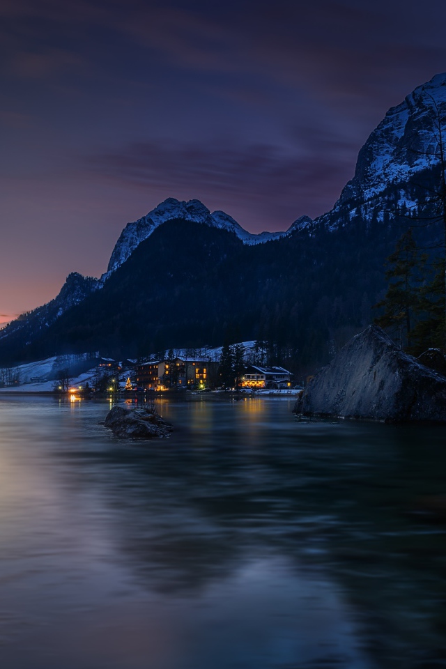 Город у озера на фоне заснеженных гор ночью 