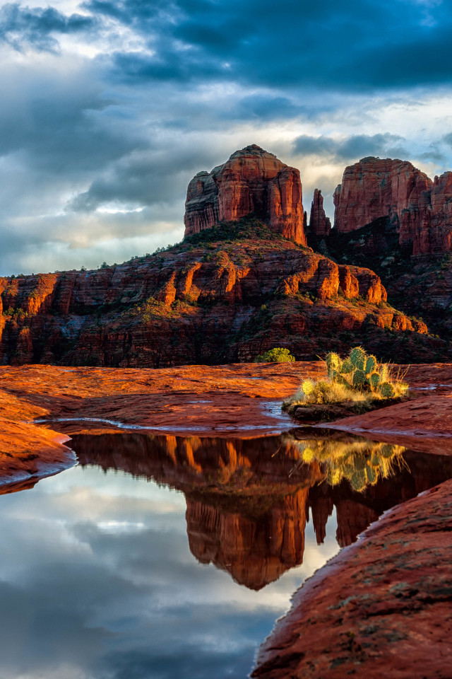 Скалы под пасмурным небом отражаются в воде
