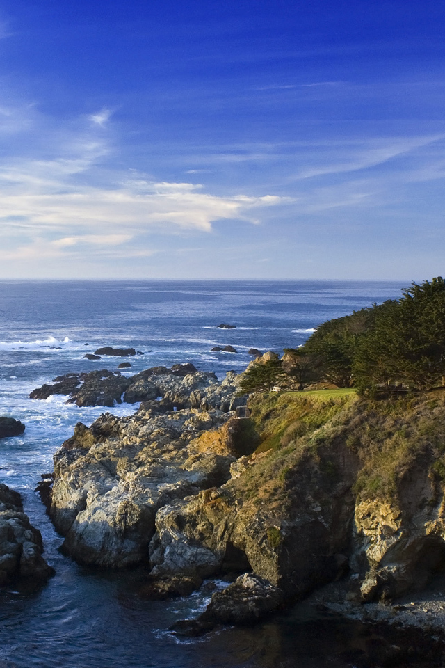 Каменные скалы береговой линии в океане под голубым небом