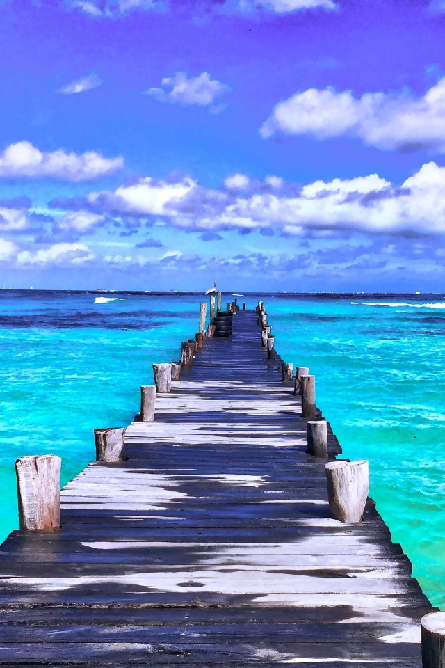 Деревянный мокрый пирс в голубом океане под красивым небом