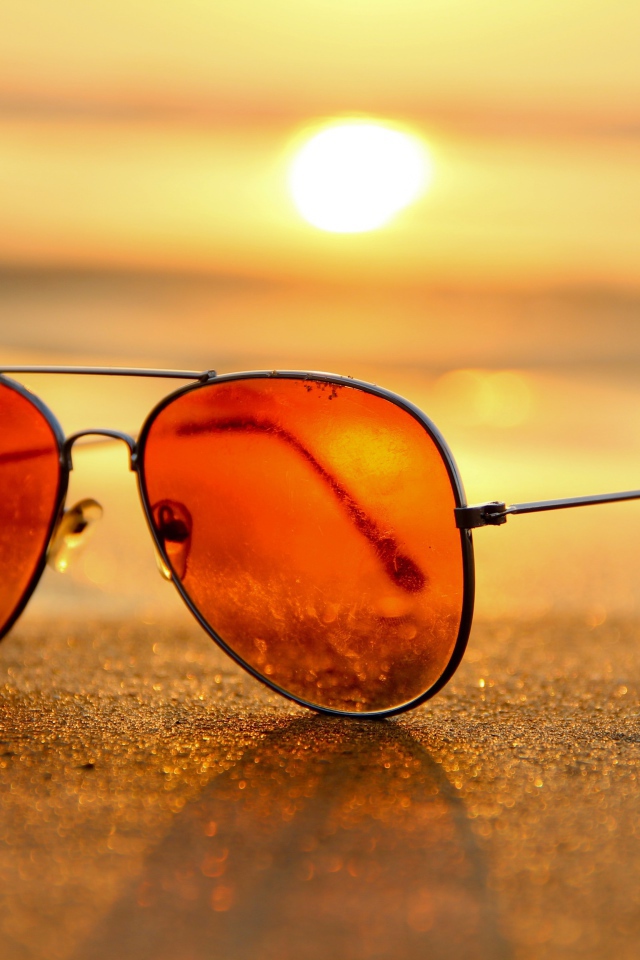 Солнечные очки лежат на горячем морском песке