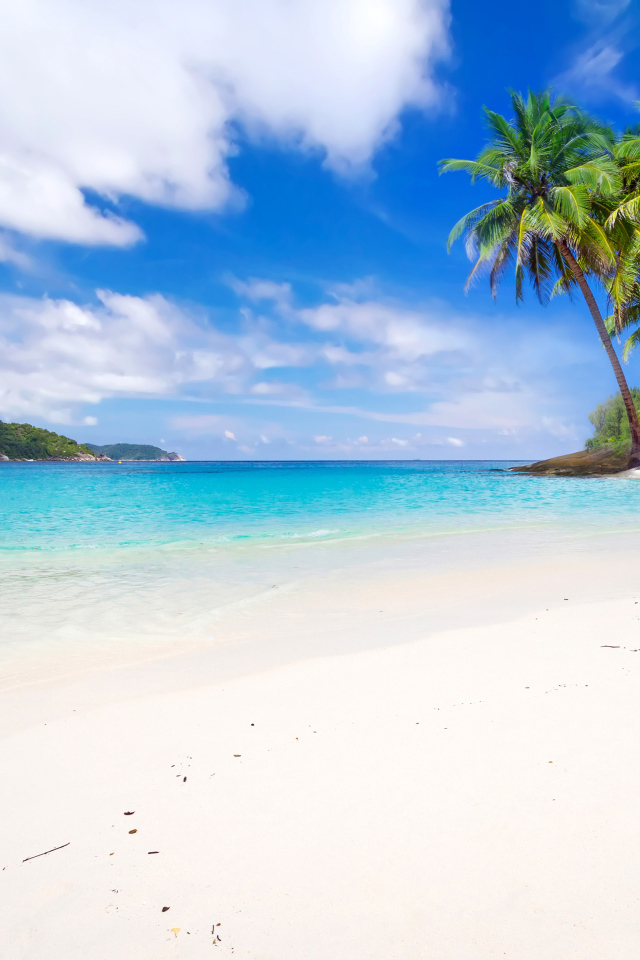 Белый песок на тропическом пляже с голубой водой 