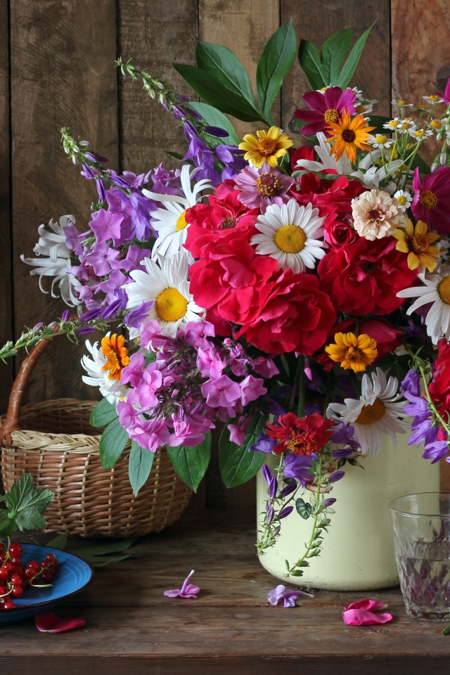 Красивый букет стоит на  столе с красной смородиной