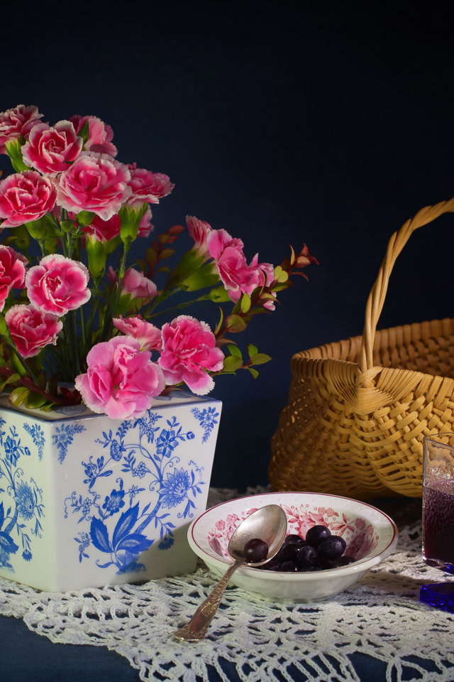 Букет гвоздик в красивой вазе на столе с корзиной и соком