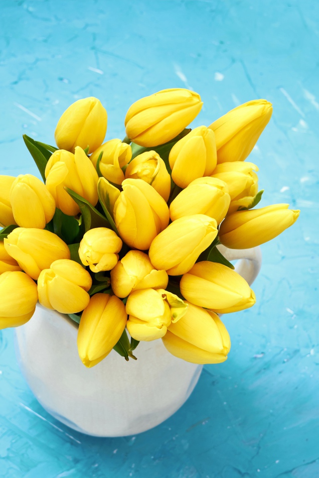 Букет оранжевых тюльпанов в белой вазе на голубом фоне