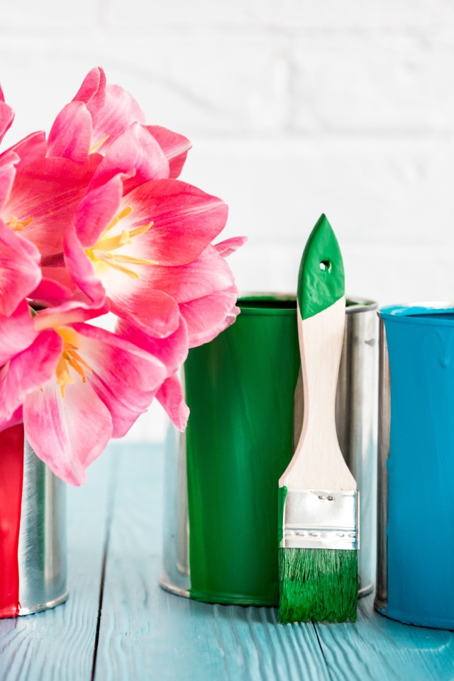 Букет розовых тюльпанов на столе с банками краски и кисточками