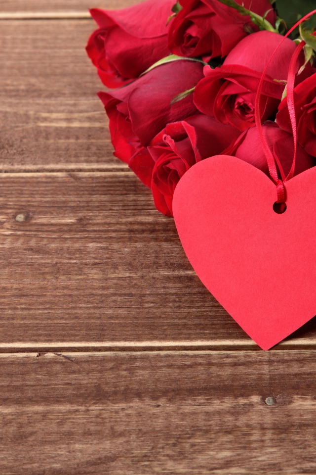 Букет красных роз на деревянном столе с красным сердцем