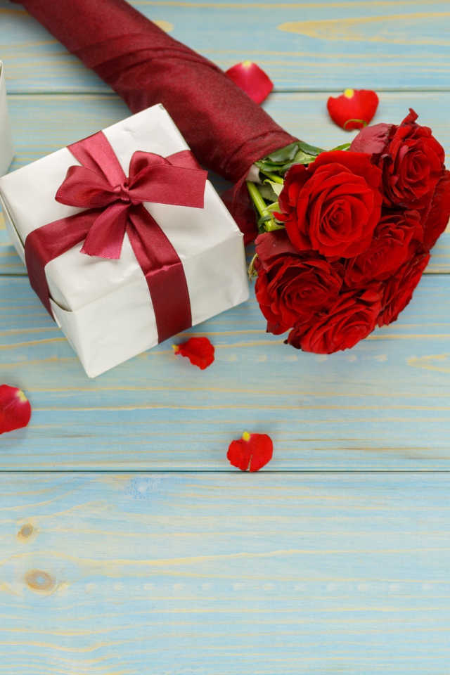 Букет красных роз с подарками на столе