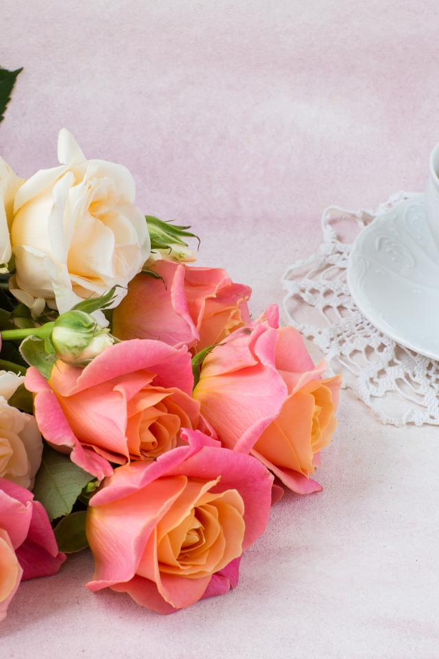 Красивый букет нежных роз на столе с чашкой чая