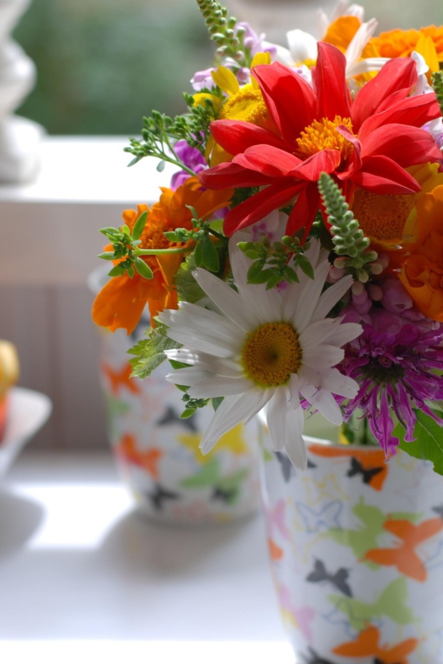 Букет разноцветных  садовых цветов в вазе на столе 