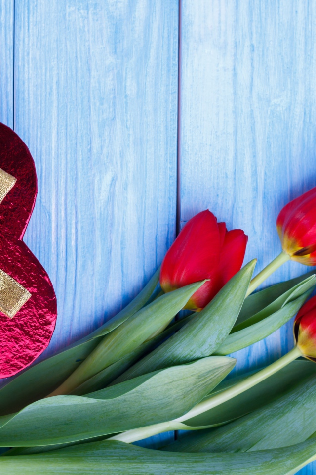 Букет красных тюльпанов на синем фоне с подарком в форме сердца