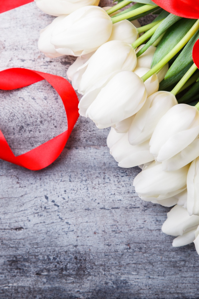 Букет белых тюльпанов с красным бантом на сером столе