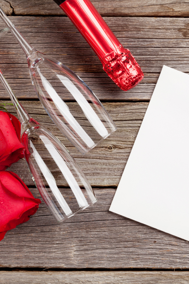 Белый лист бумаги на деревянном столе с бокалами и красными розами