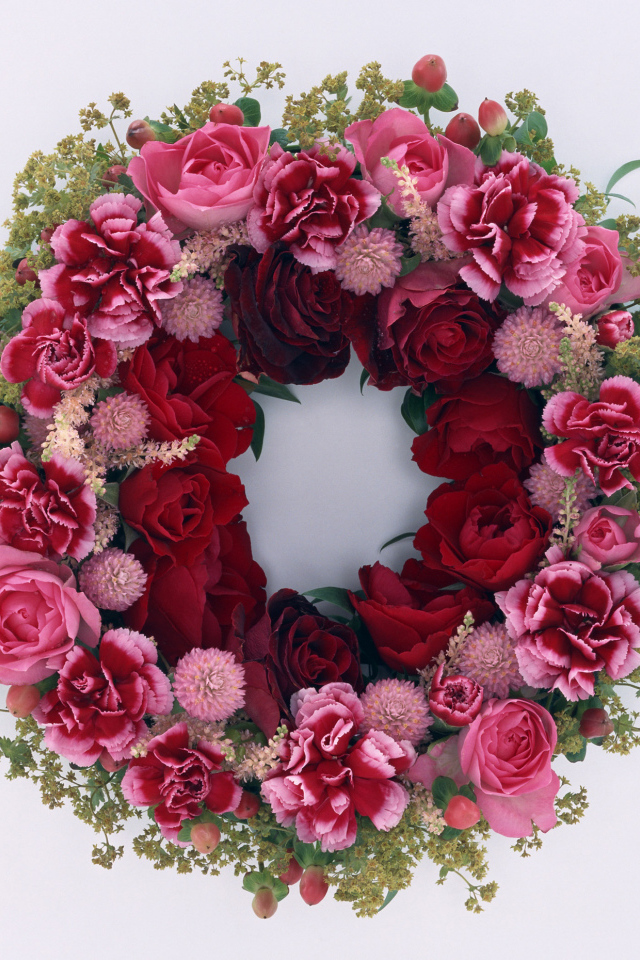 Венок и красных роз с цветами гвоздики на сером фоне