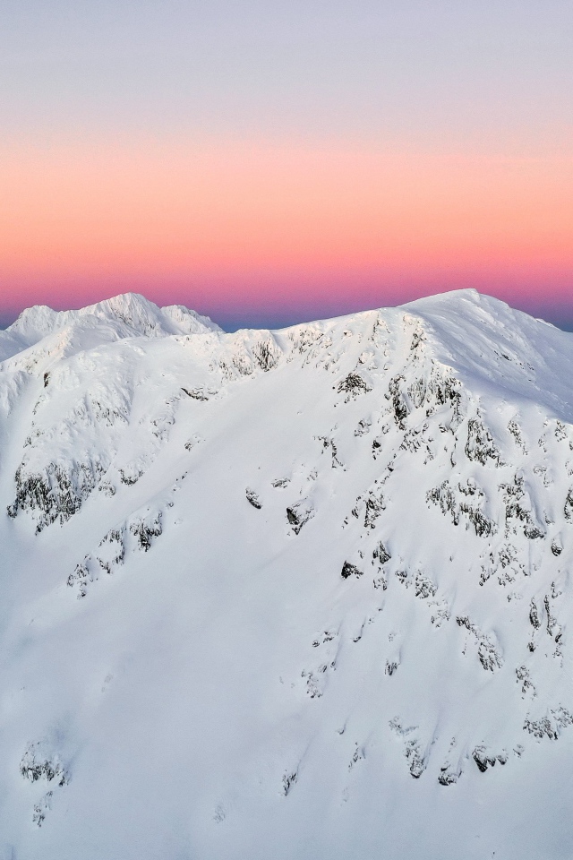 Красивые заснеженные вершины горы на фоне розового неба