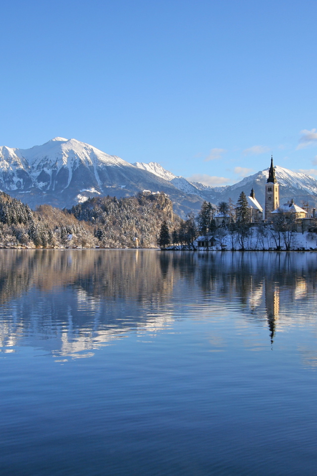 Красивый вид на заснеженные горы и замок у озера 
