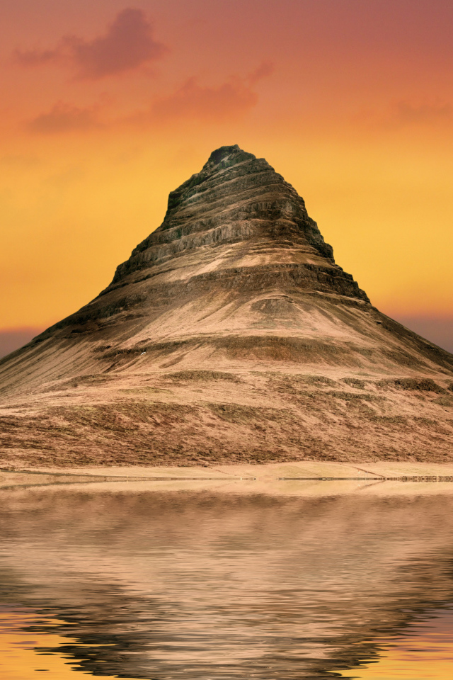 Гора отражается в воде на фоне неба на закате