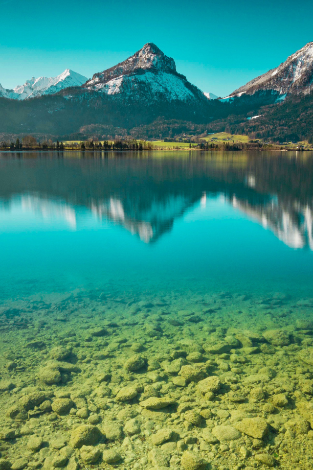 Snow-capped mountains are reflected in the clear water of the lake.
