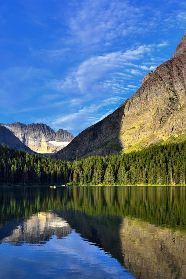 Каменные горы под голубым небом отражаются в воде