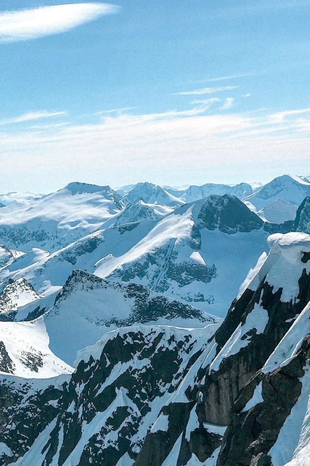 Верхушки заснеженных гор в лучах солнца под голубым небом 