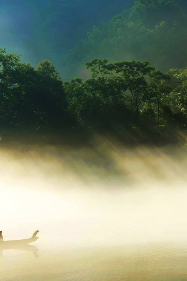 Лодка на туманном озере в лучах солнца 