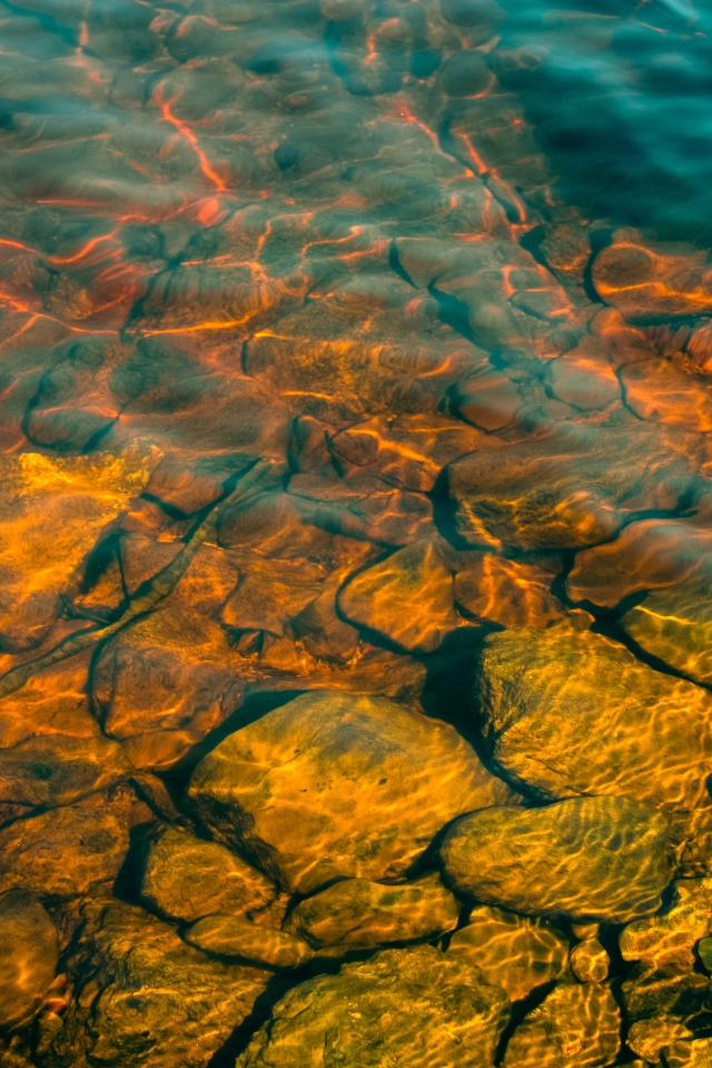 Камни на дне озера с чистой водой в лучах солнца