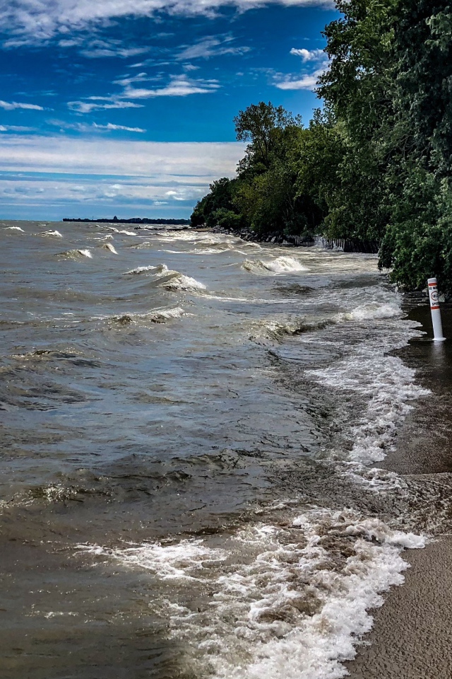 Морские волны омывают берег под голубым небом 