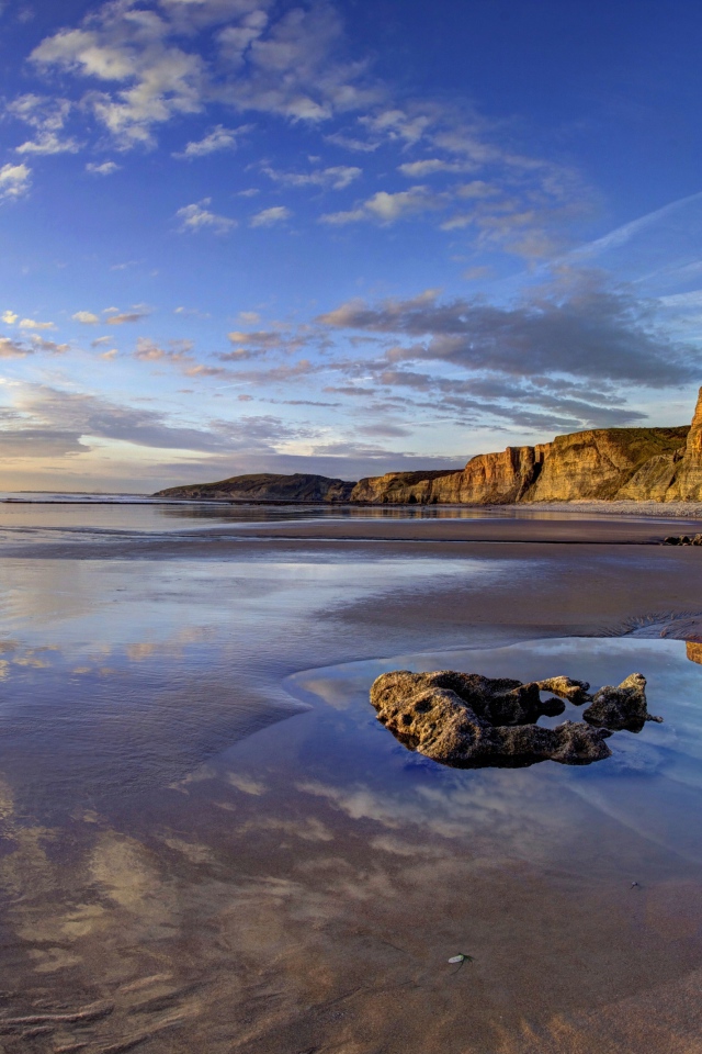 Мокрый морской берег со скалами на закате
