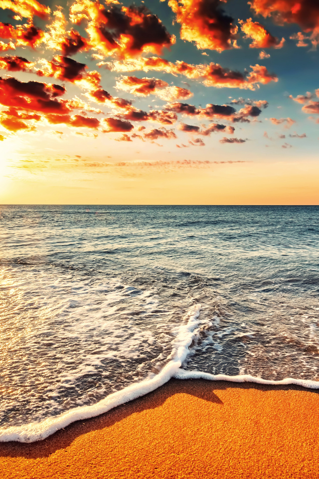 Белая морская пена на оранжевом песке под красивым небом