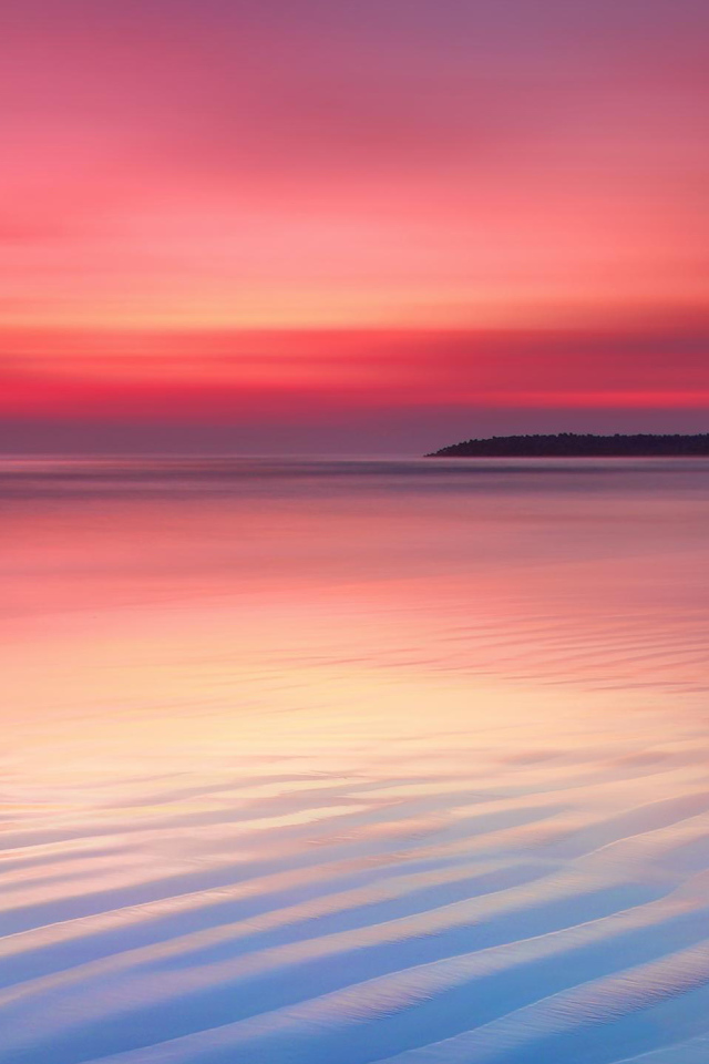 Мокрый белый песок на берегу океана на закате