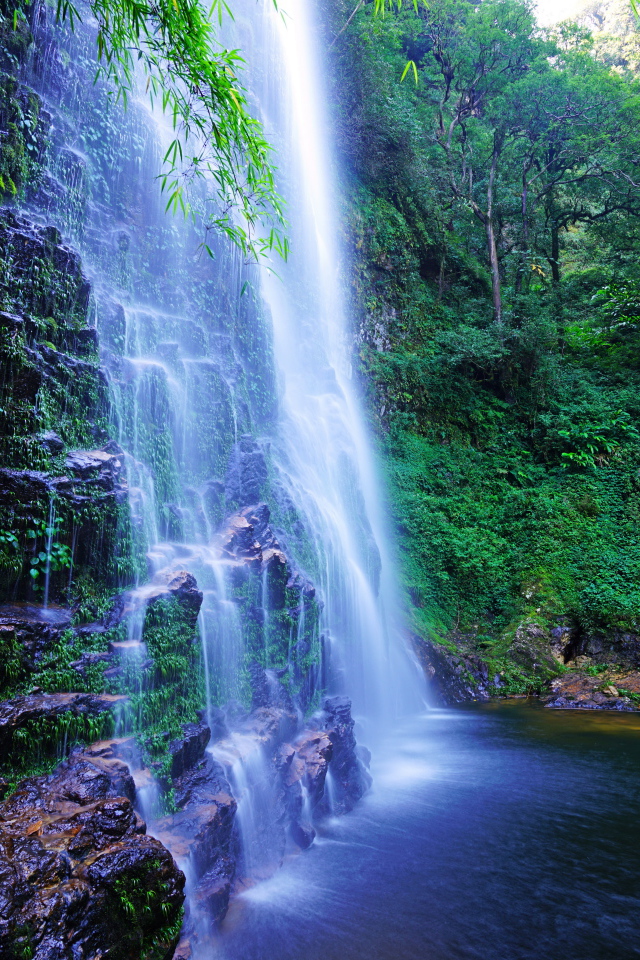 Быстрый водопад стекает по мокрым камням со скалы