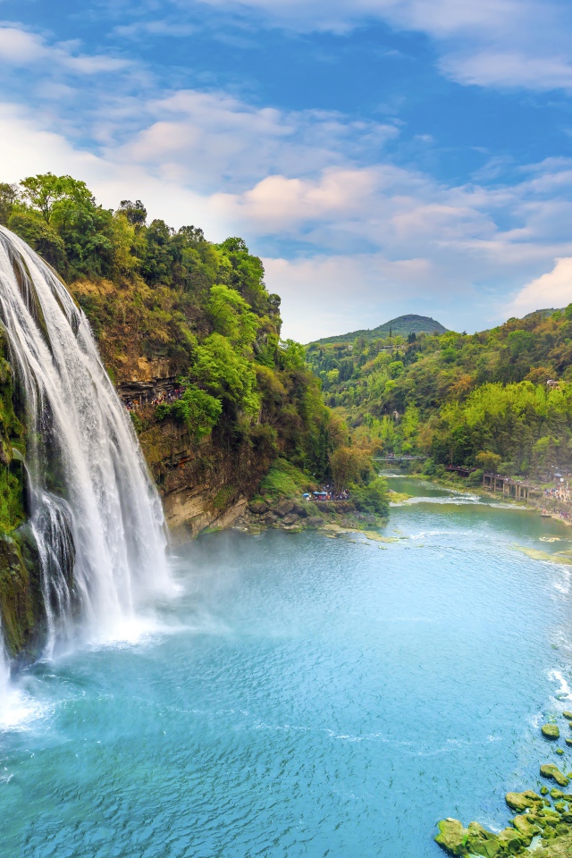 Быстрый водопад стекает с зеленых гор в реку