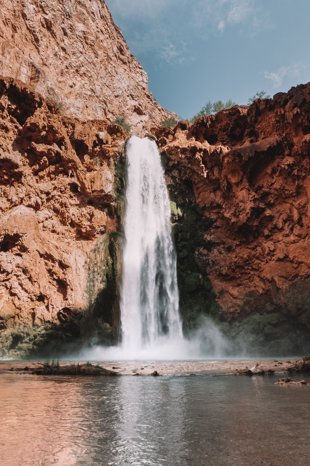 Водопад стекает со скалы в озеро 