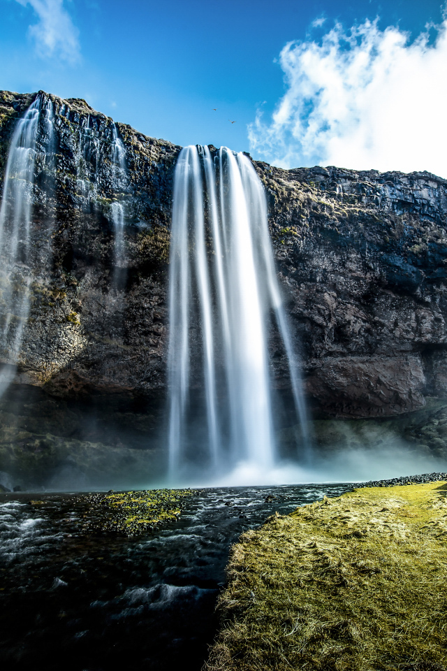 Водопад стекает с гор на фоне голубого неба