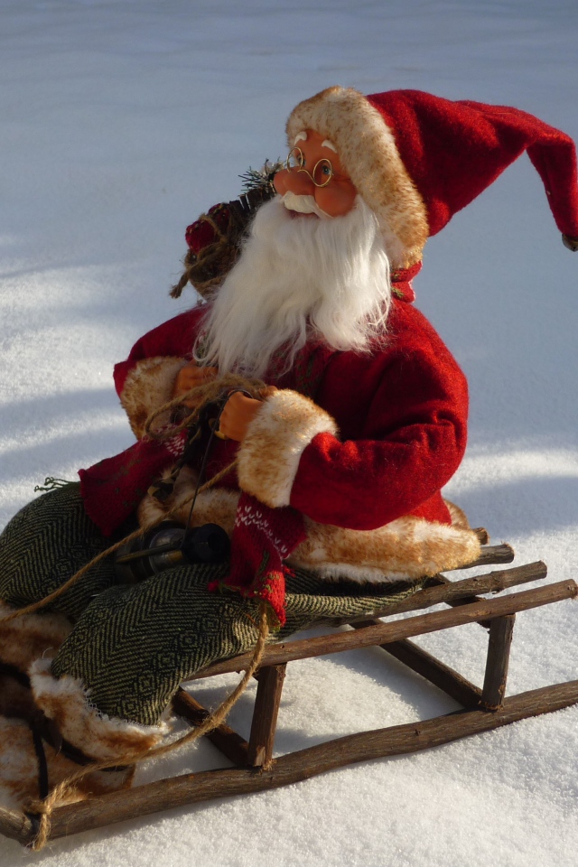 Игрушка деда Мороза на санках стоит на снегу