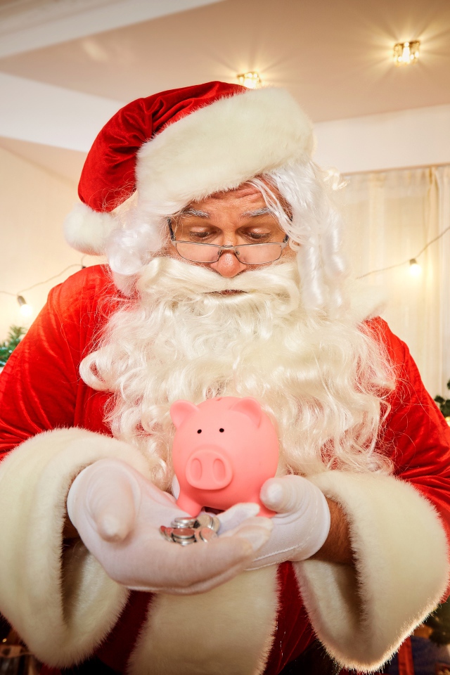 Дед Мороз со свиньей копилкой в руках у новогодней елки