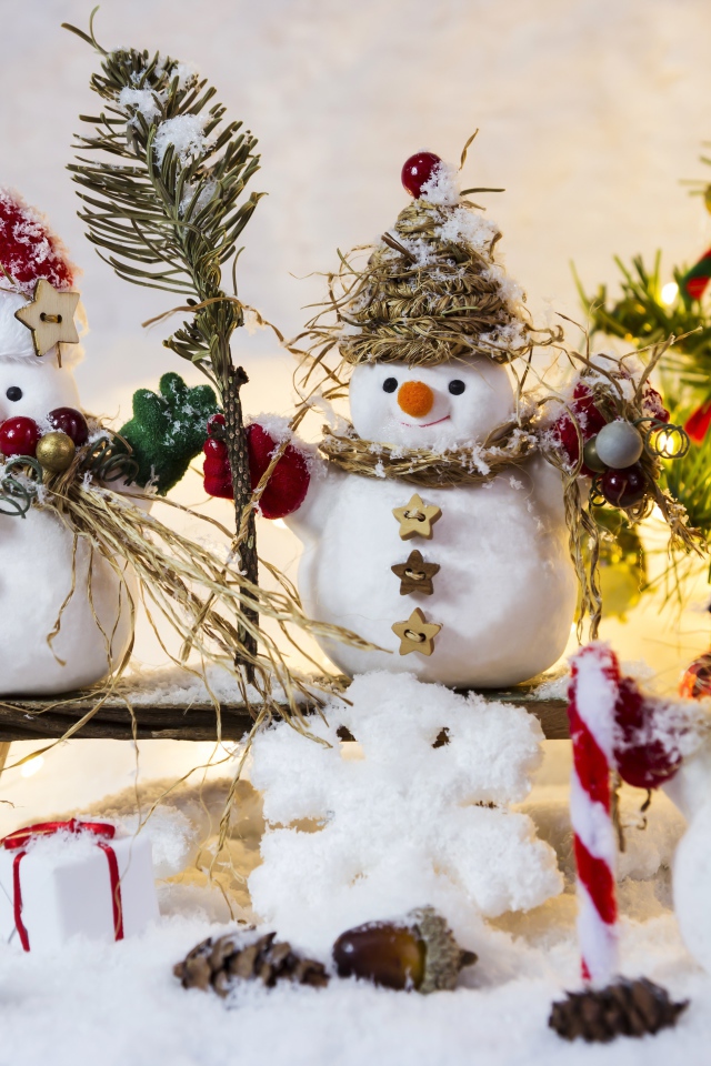 Три снеговика на снегу у искусственной елки на Новый год 