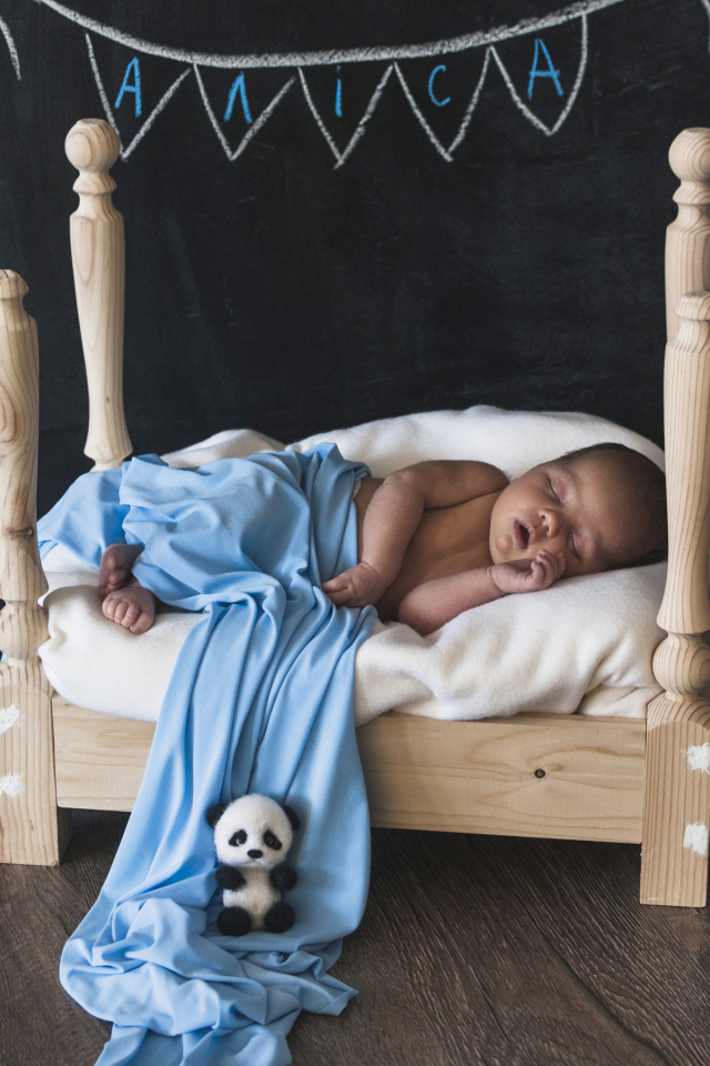 Грудной ребенок спит на деревянной кровати